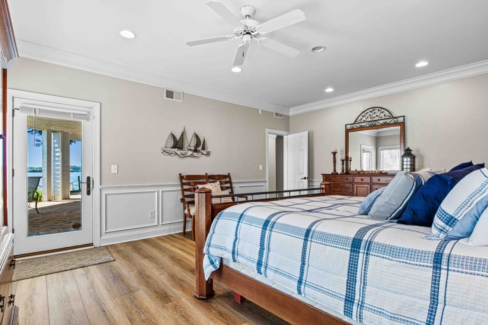 A bedroom with a bed, chair and mirror.