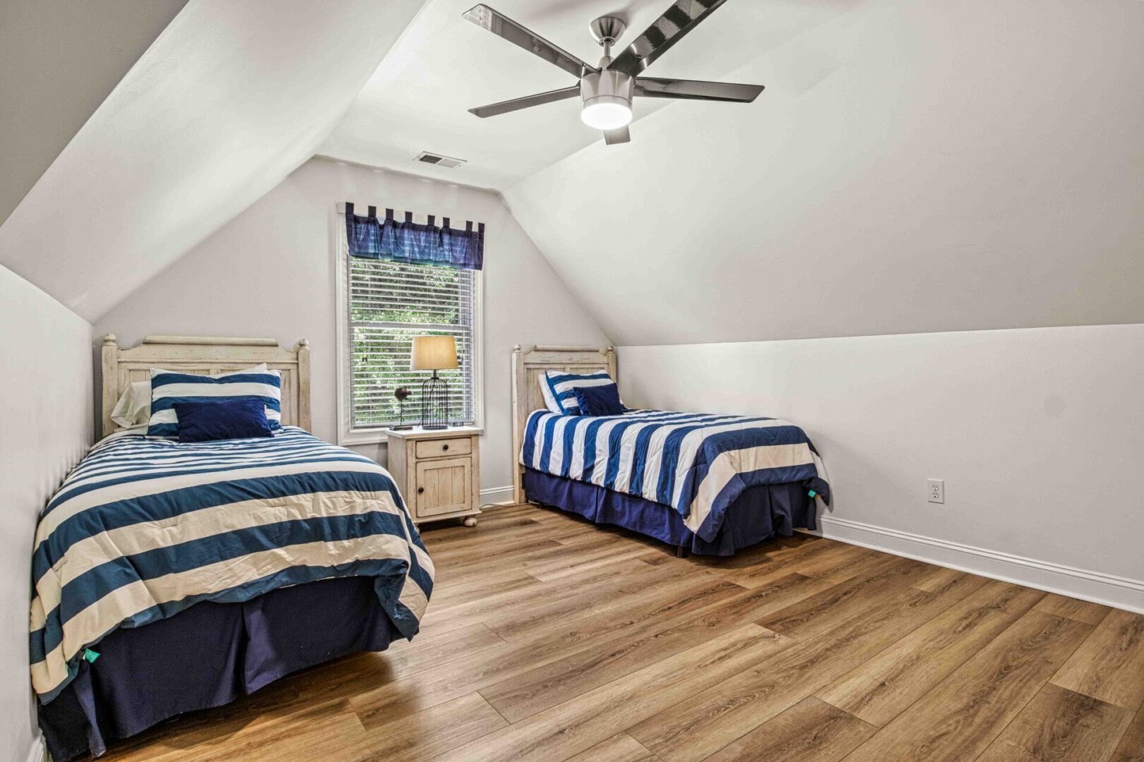 A bedroom with two beds and a ceiling fan.