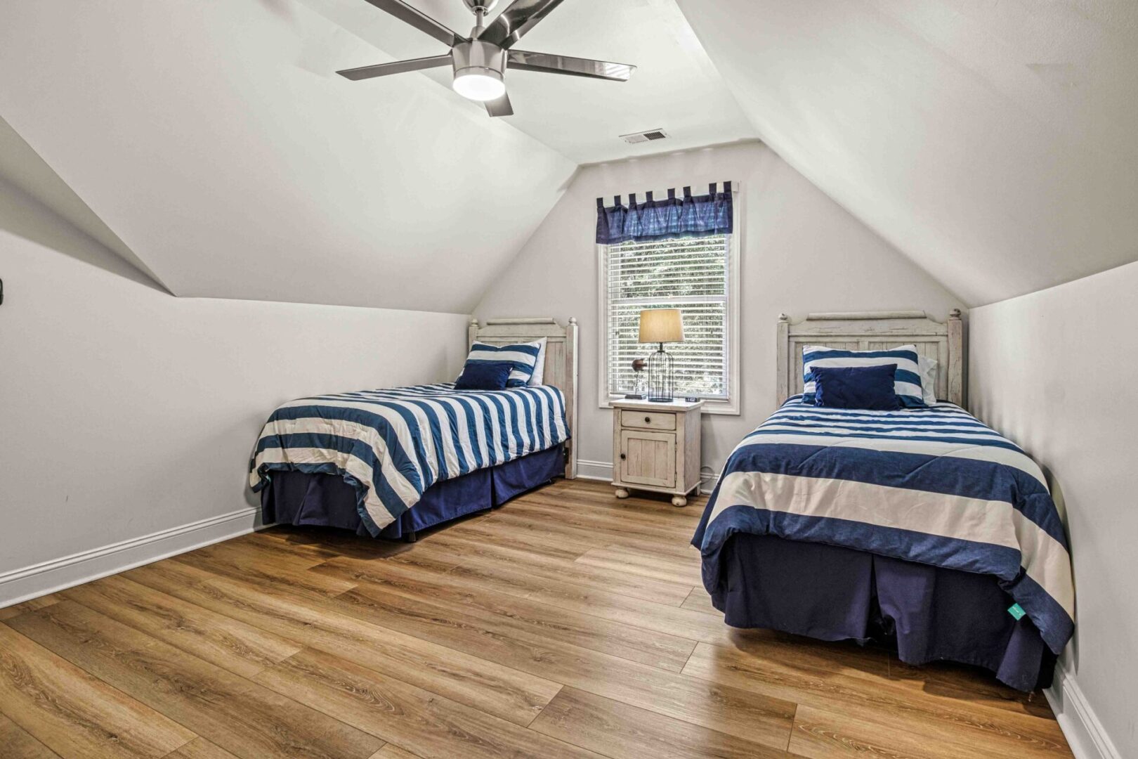 A bedroom with two beds and a ceiling fan.