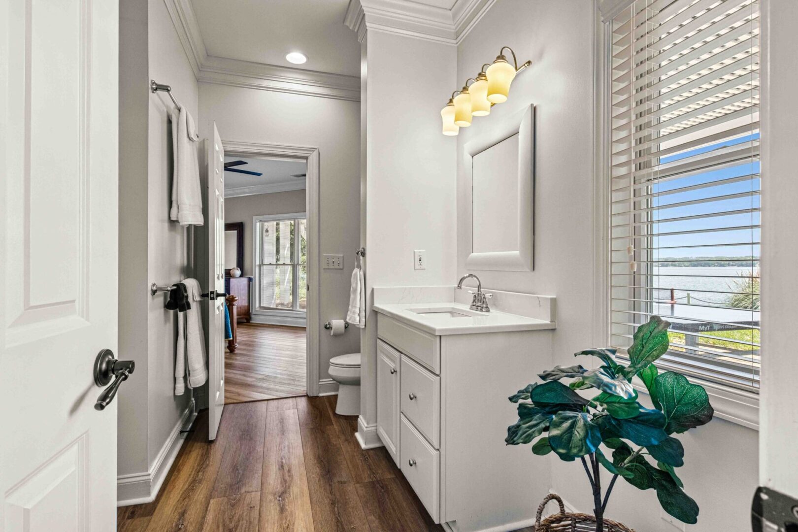 A bathroom with white cabinets and wood floors.