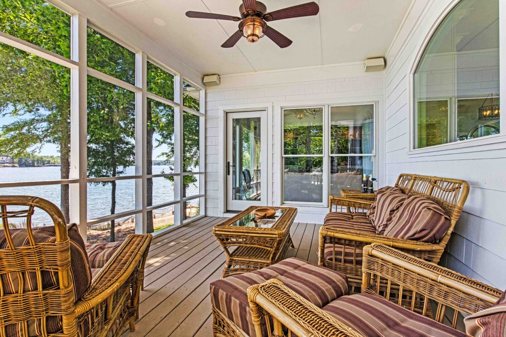 A porch with wicker furniture and a ceiling fan.