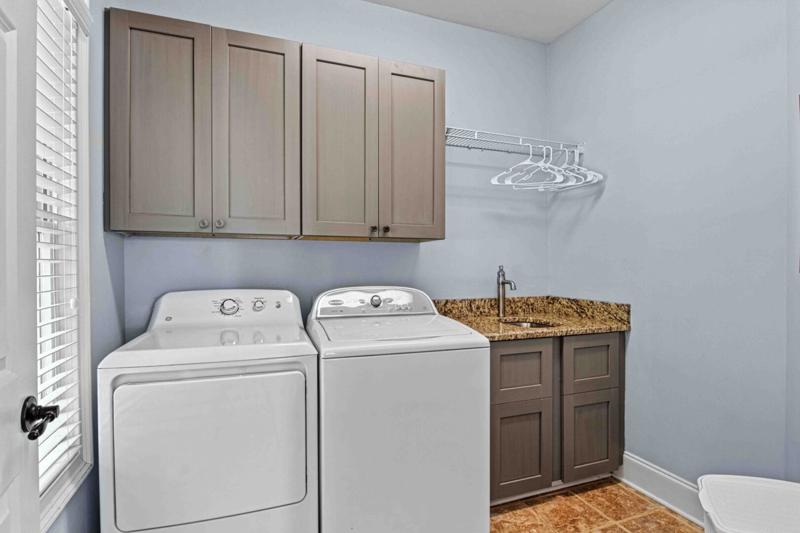 A laundry room with two machines and cabinets.