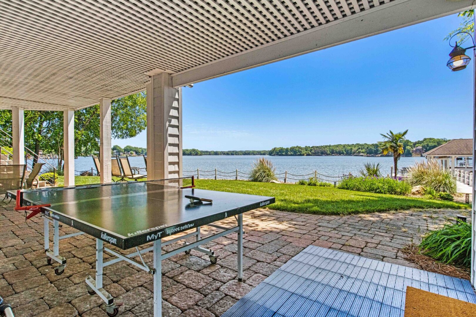 A table tennis table is in the middle of an outdoor patio.